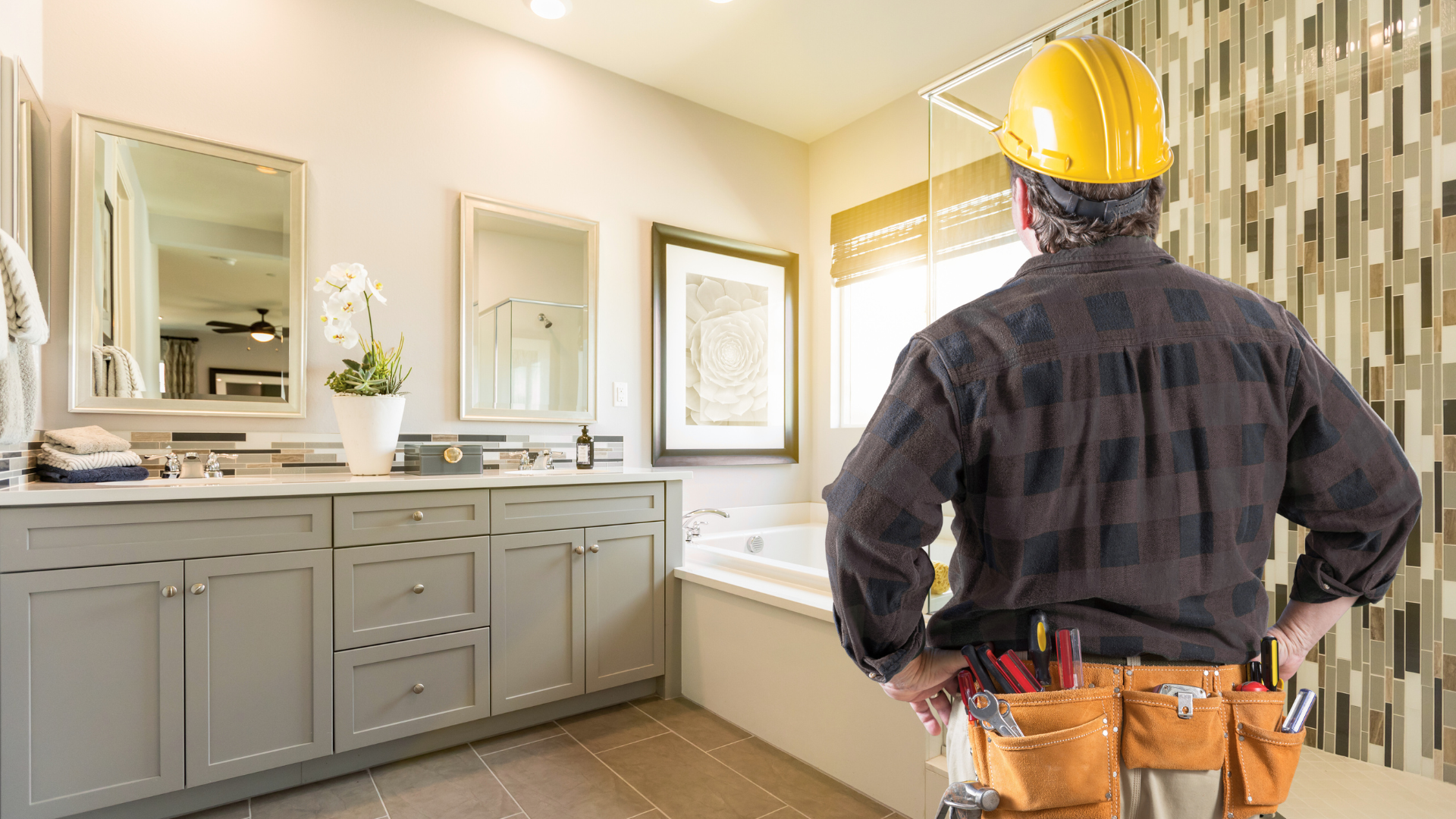 A man wearing a hard hat is standing in a bathroom.