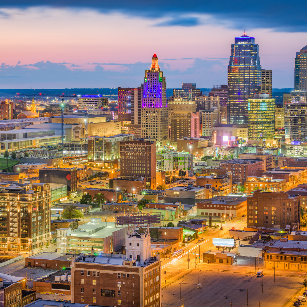 An aerial view of a city at night with a purple building in the foreground.