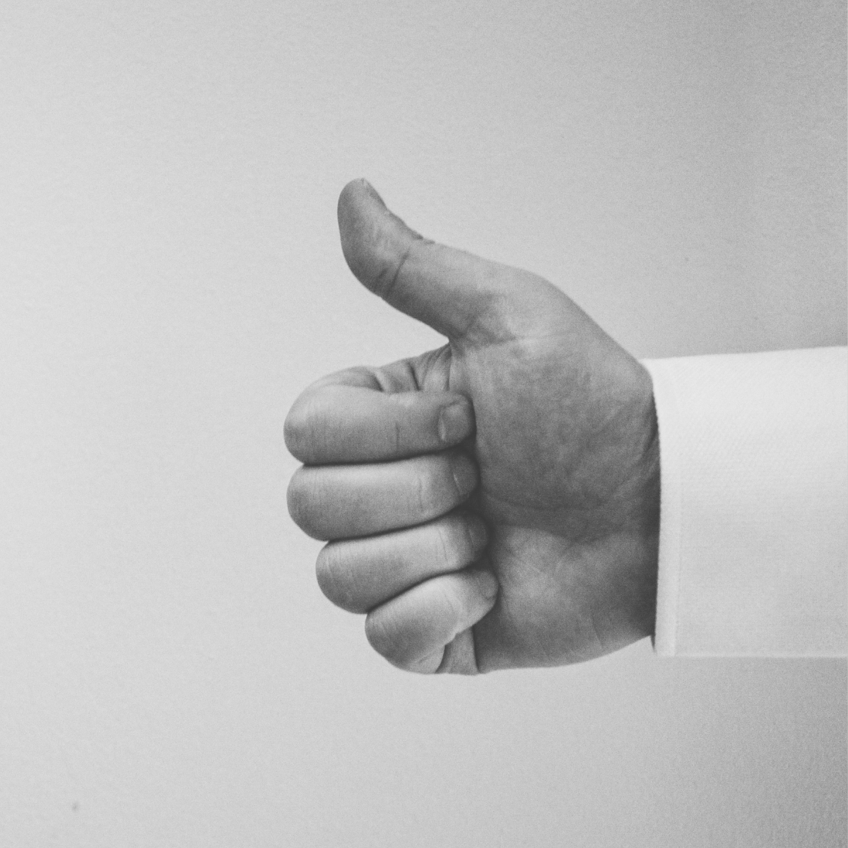 A black and white photo of a hand giving a thumbs up