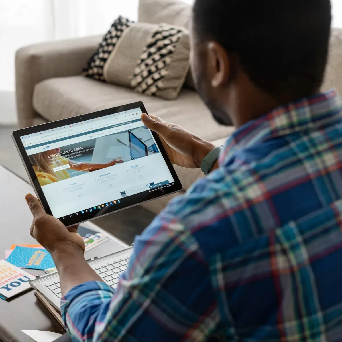 A man is sitting at a table using a tablet computer.