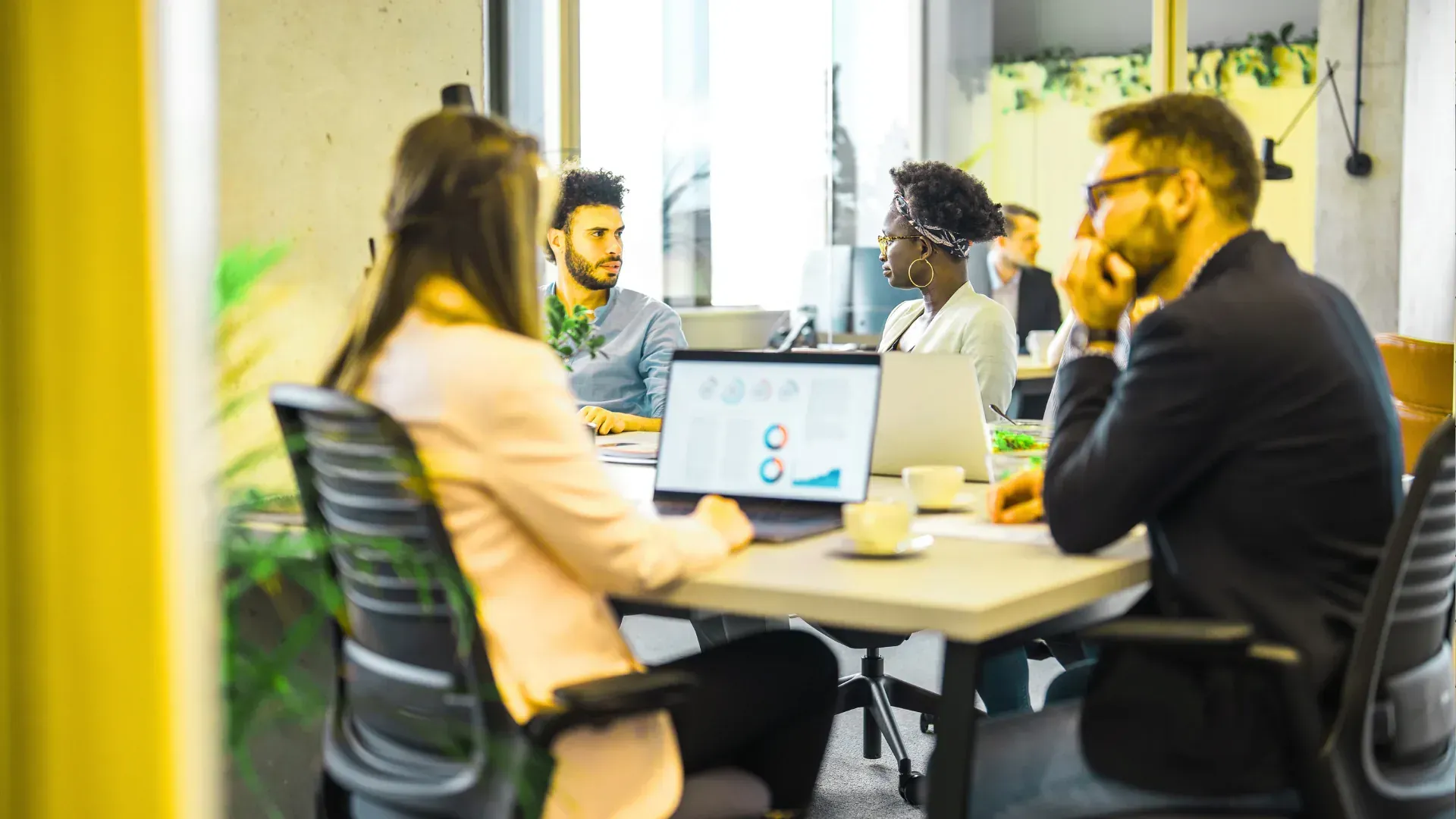 A group of people are sitting around a table with laptops.
