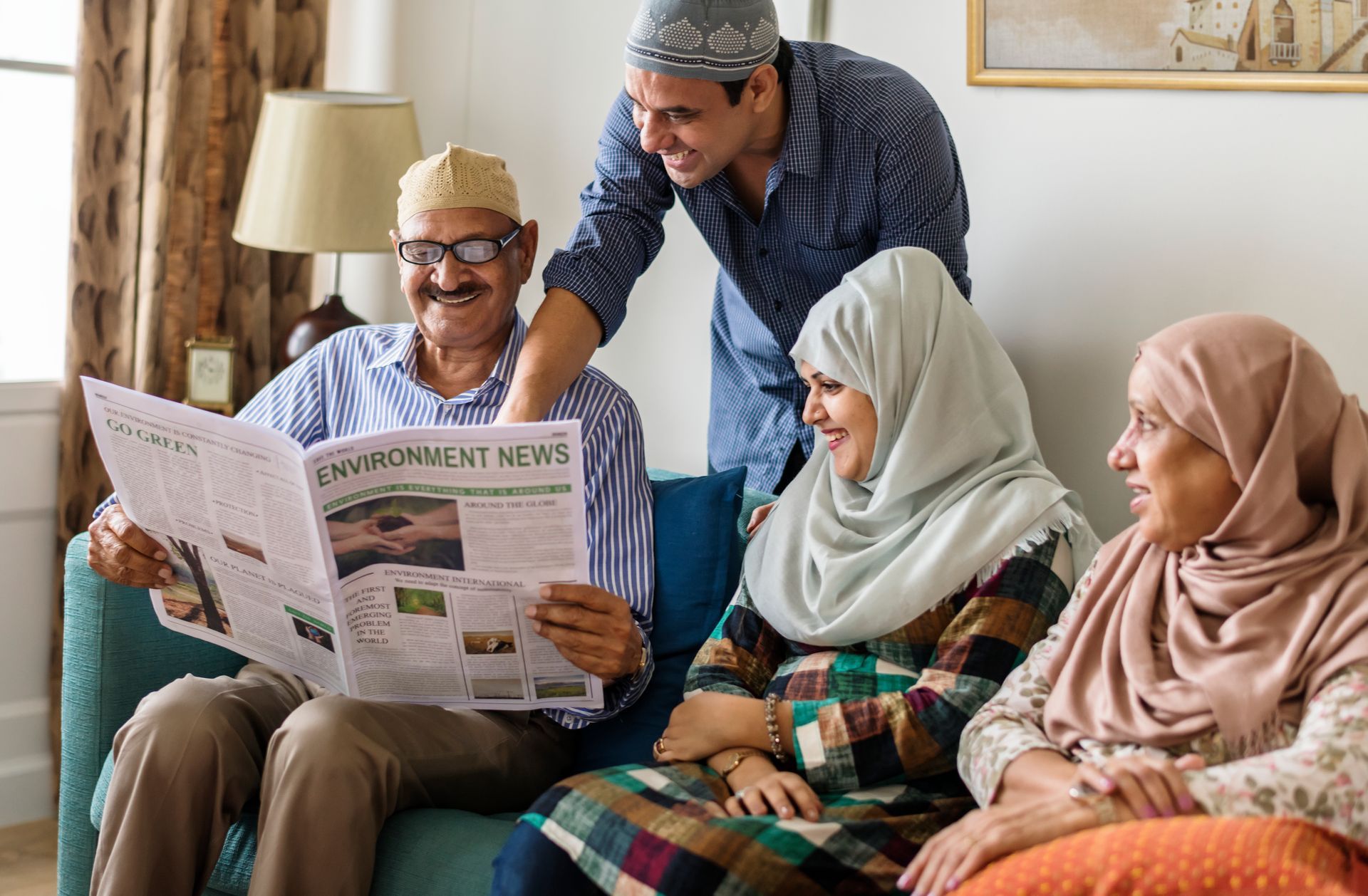 A group of people are sitting on a couch reading a newspaper.
