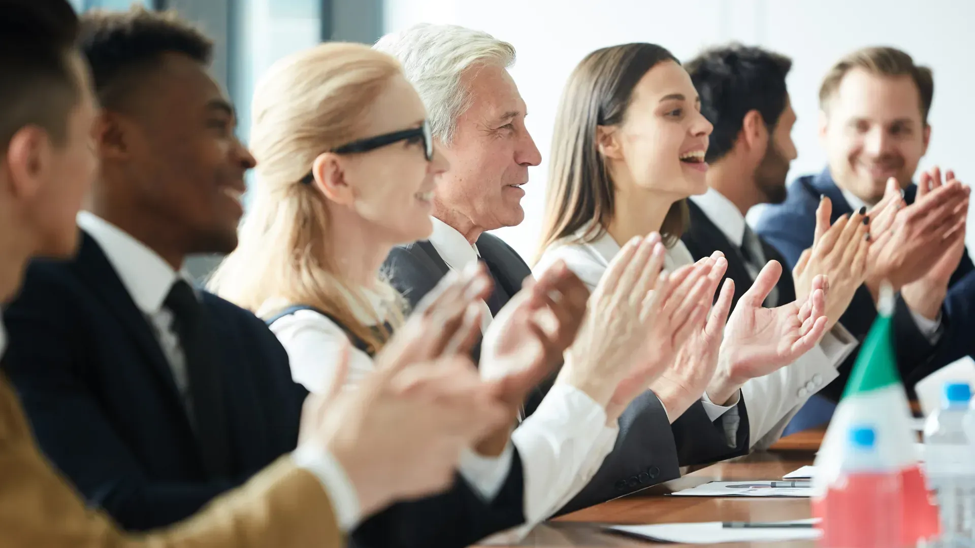 A group of people are sitting at a table clapping their hands.