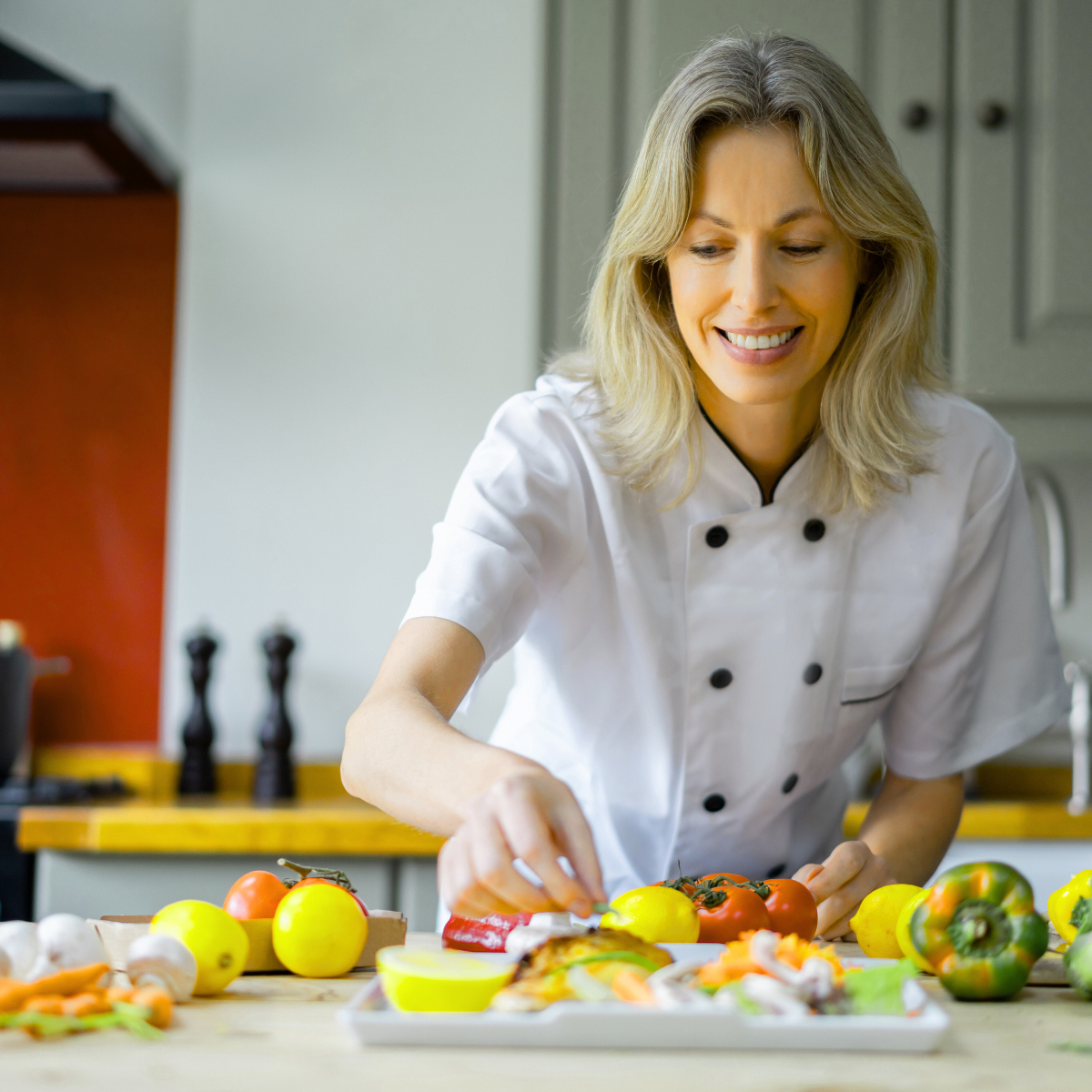 A woman in a chef 's uniform is preparing food in a kitchen.
