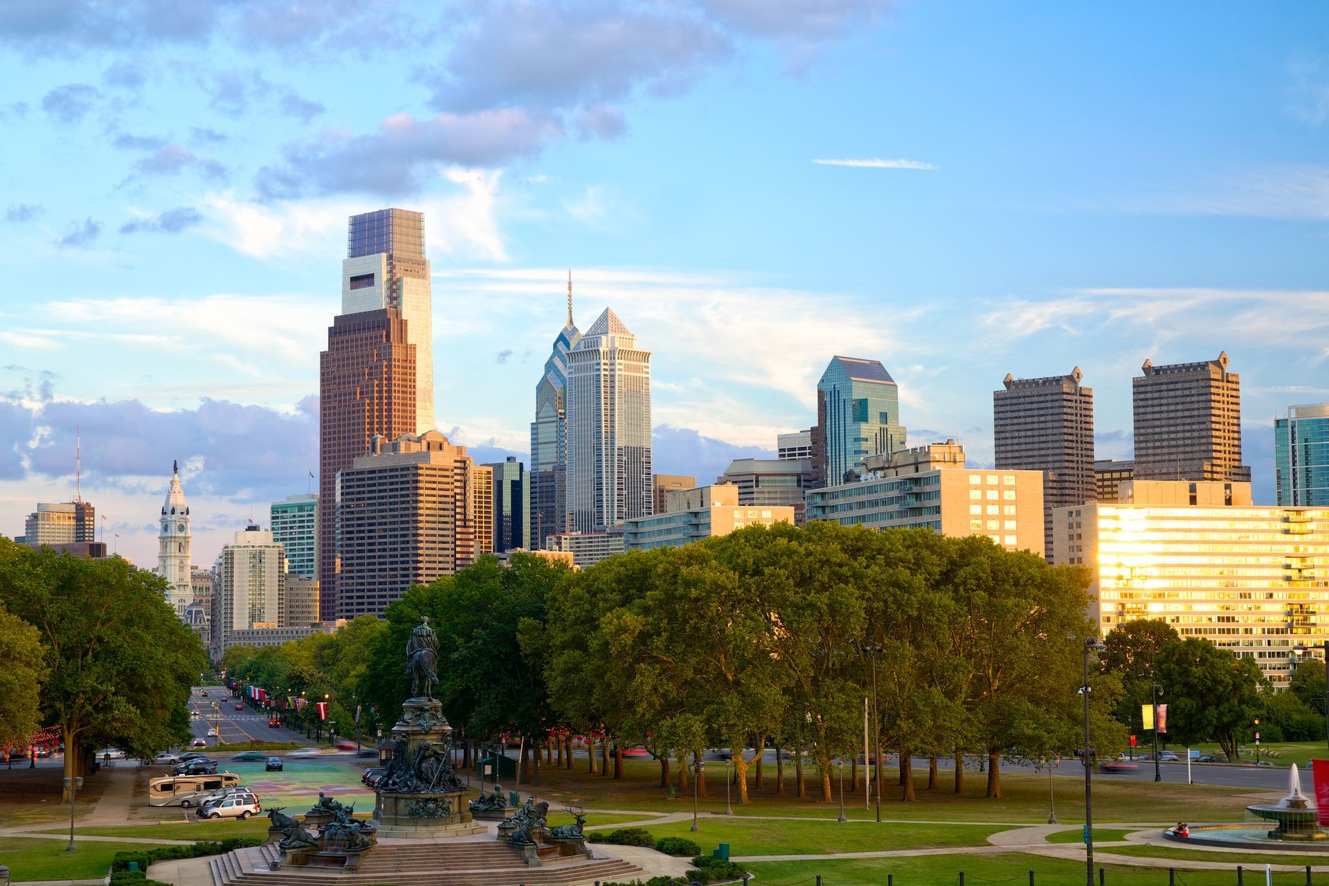 A city skyline with a fountain in the foreground and a park in the background.