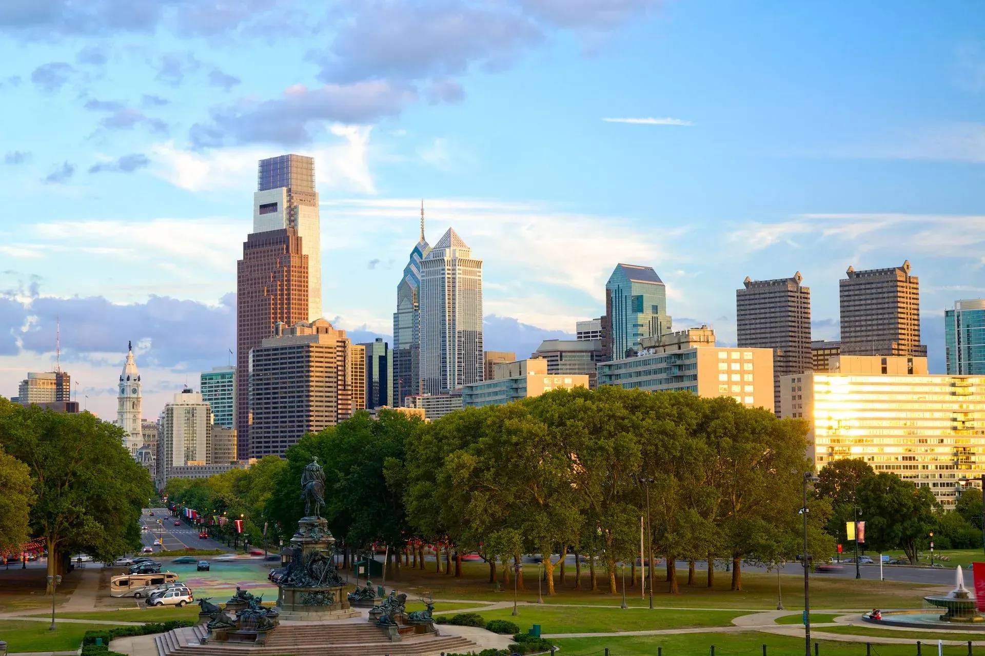 A city skyline with a fountain in the foreground and a park in the background.