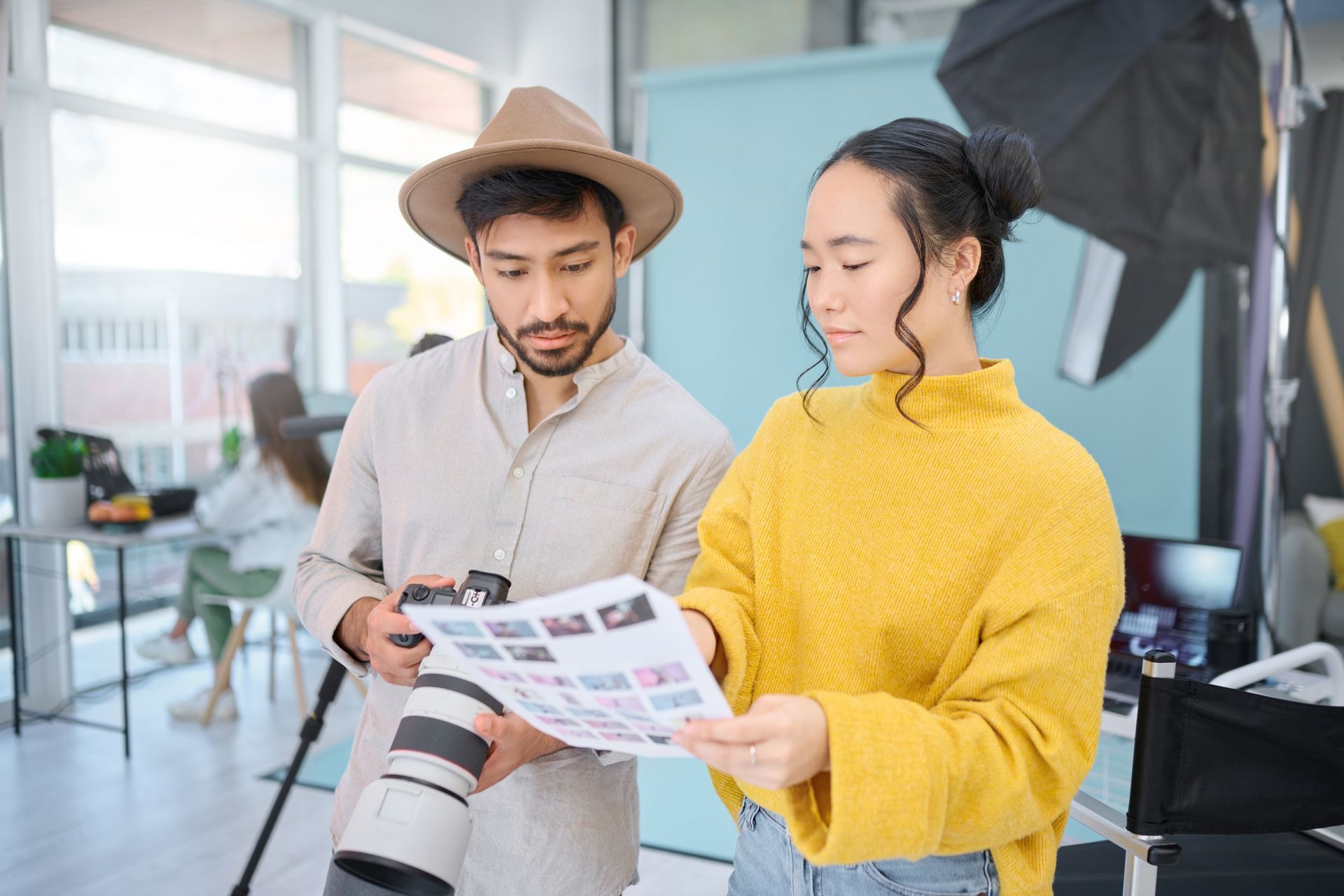 A man is holding a camera and a woman is holding a piece of paper.