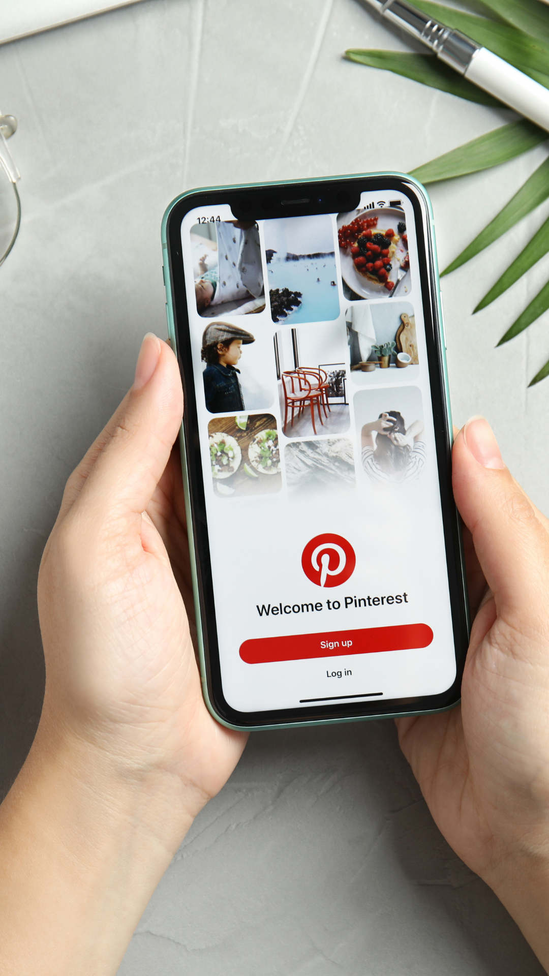 A person is holding a cell phone with pinterest on the screen.