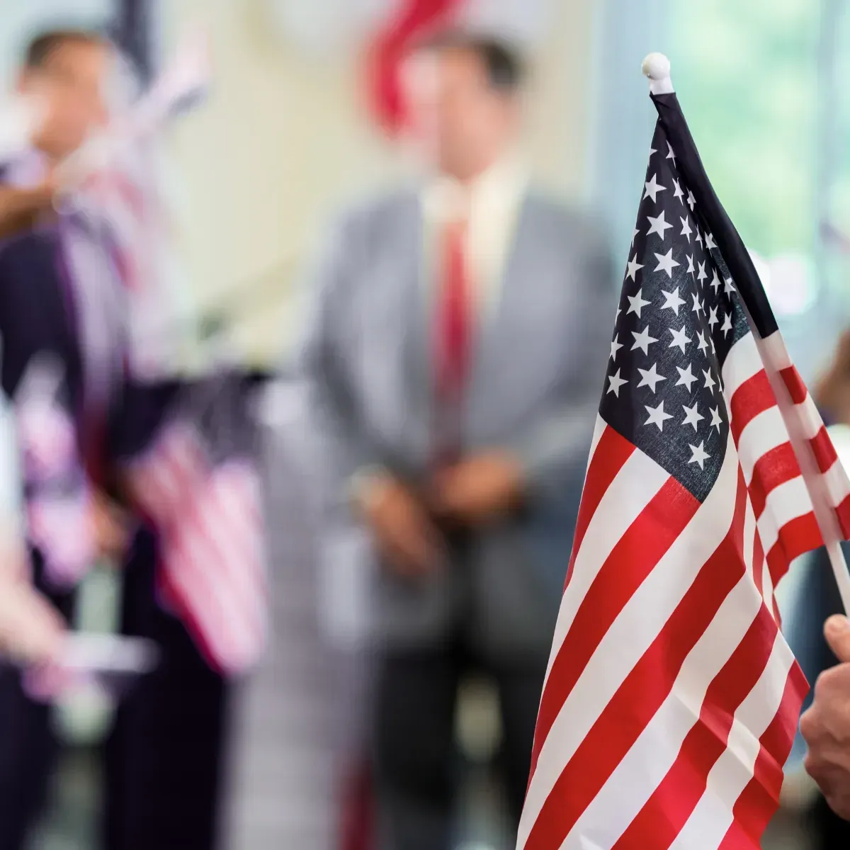A person holding an american flag in front of a group of people