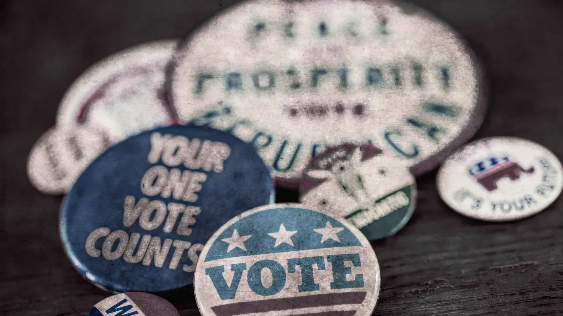 A bunch of buttons on a table with one that says `` your one vote counts ''.