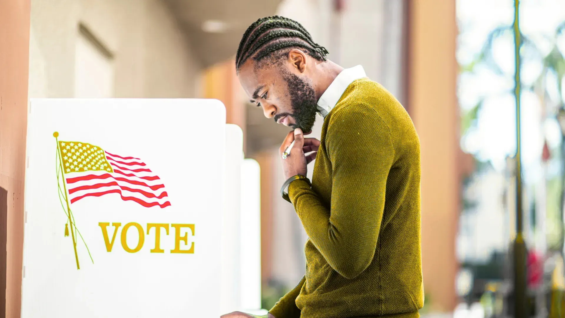 A man is standing in front of a voting booth.