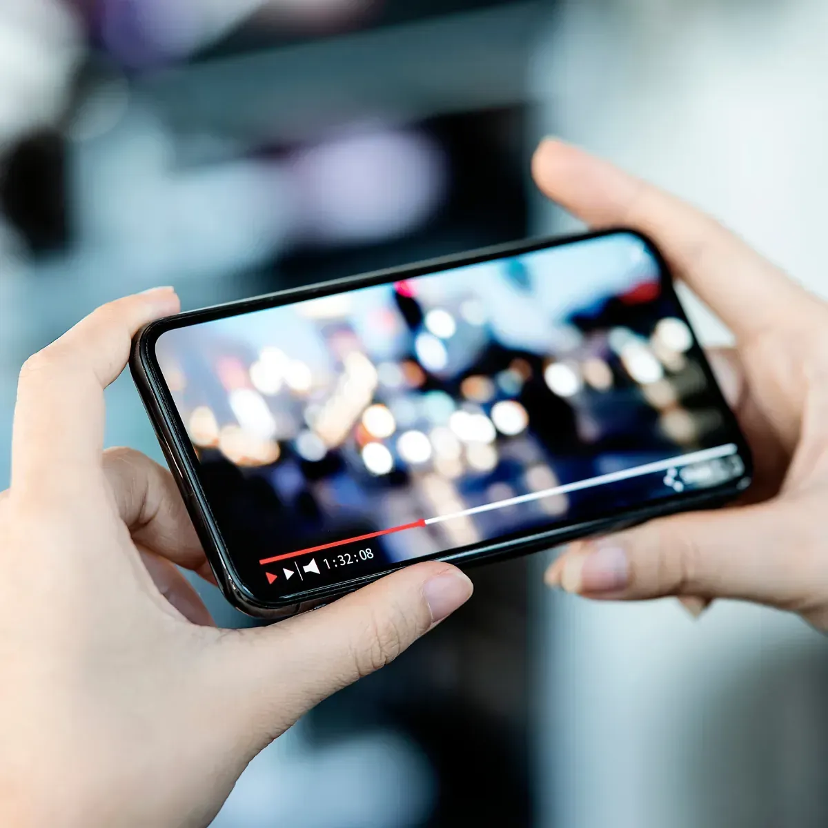 A person is holding a cell phone with a video on it