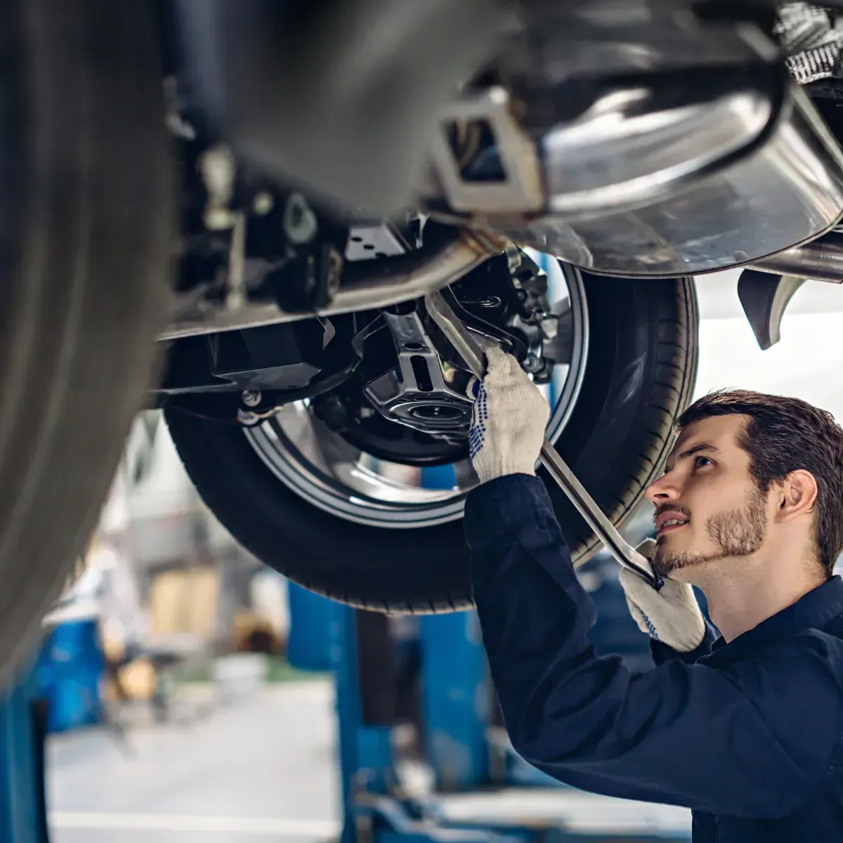 A man is working under a car with a wrench.