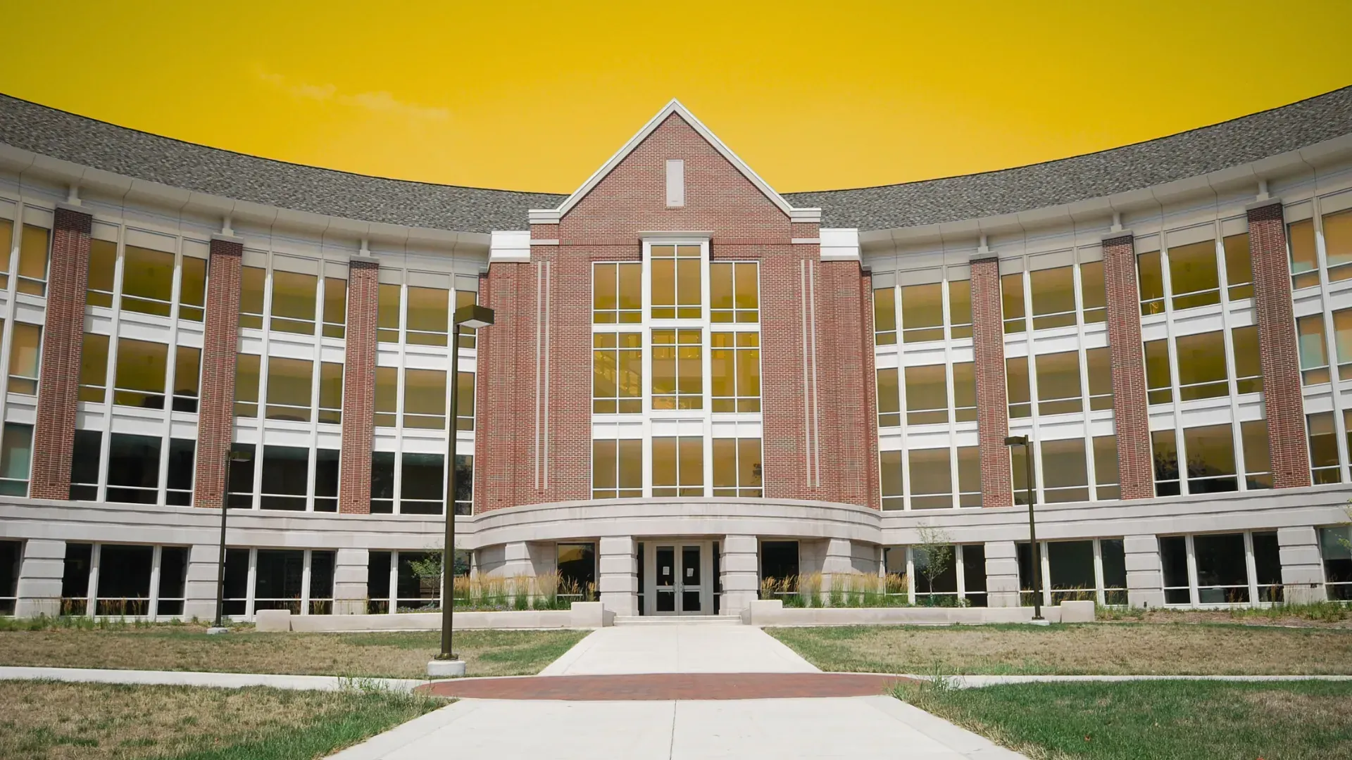 A large brick building with a lot of windows and a yellow sky in the background