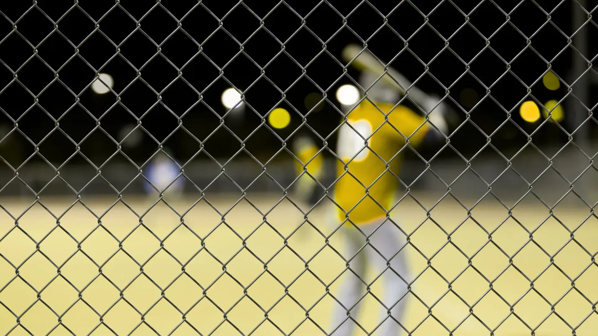 A blurry picture of a baseball player behind a chain link fence