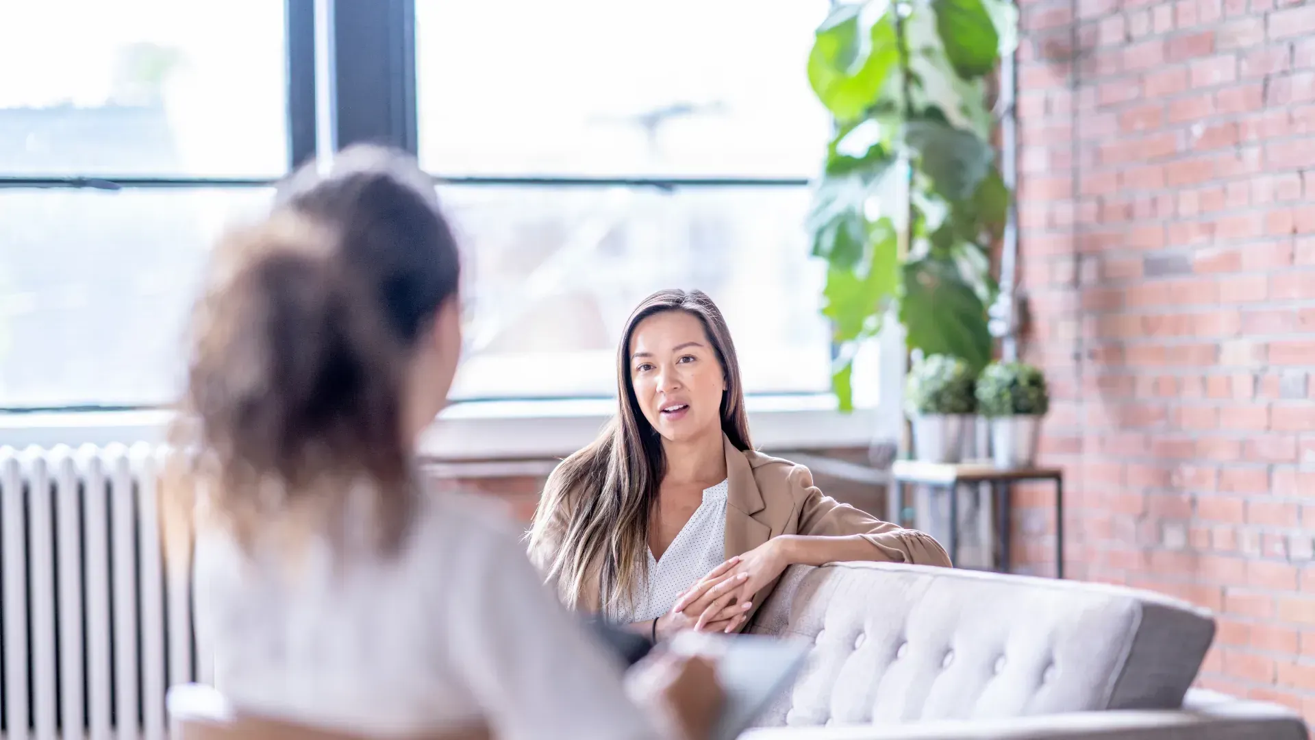 Two women are sitting on a couch having a conversation.