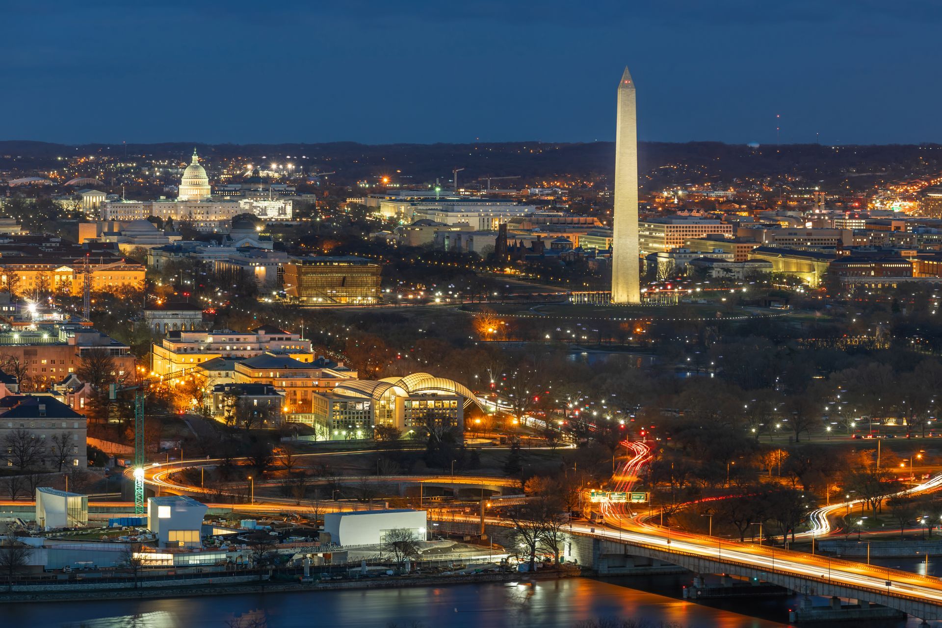 An aerial view of washington d.c. at night with the washington monument in the foreground.