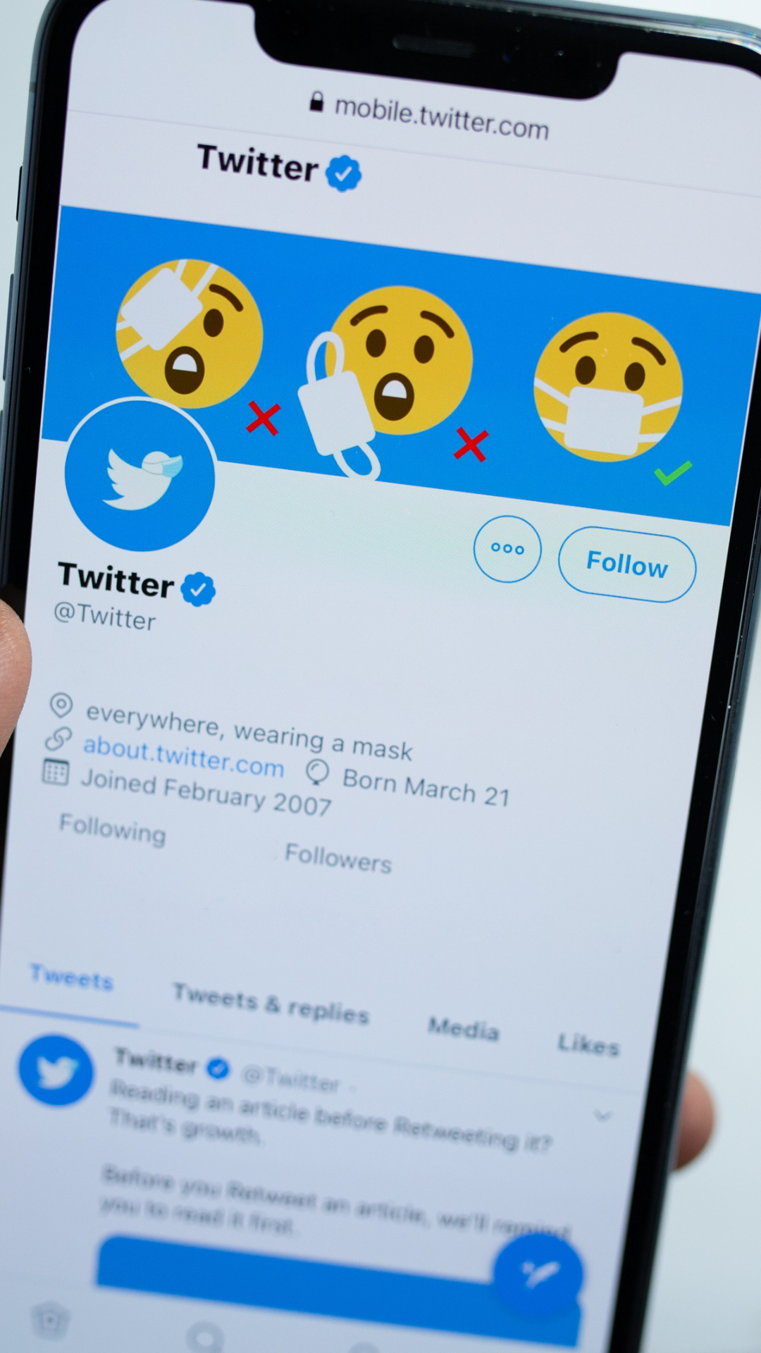 A person is holding a cell phone with the twitter app open