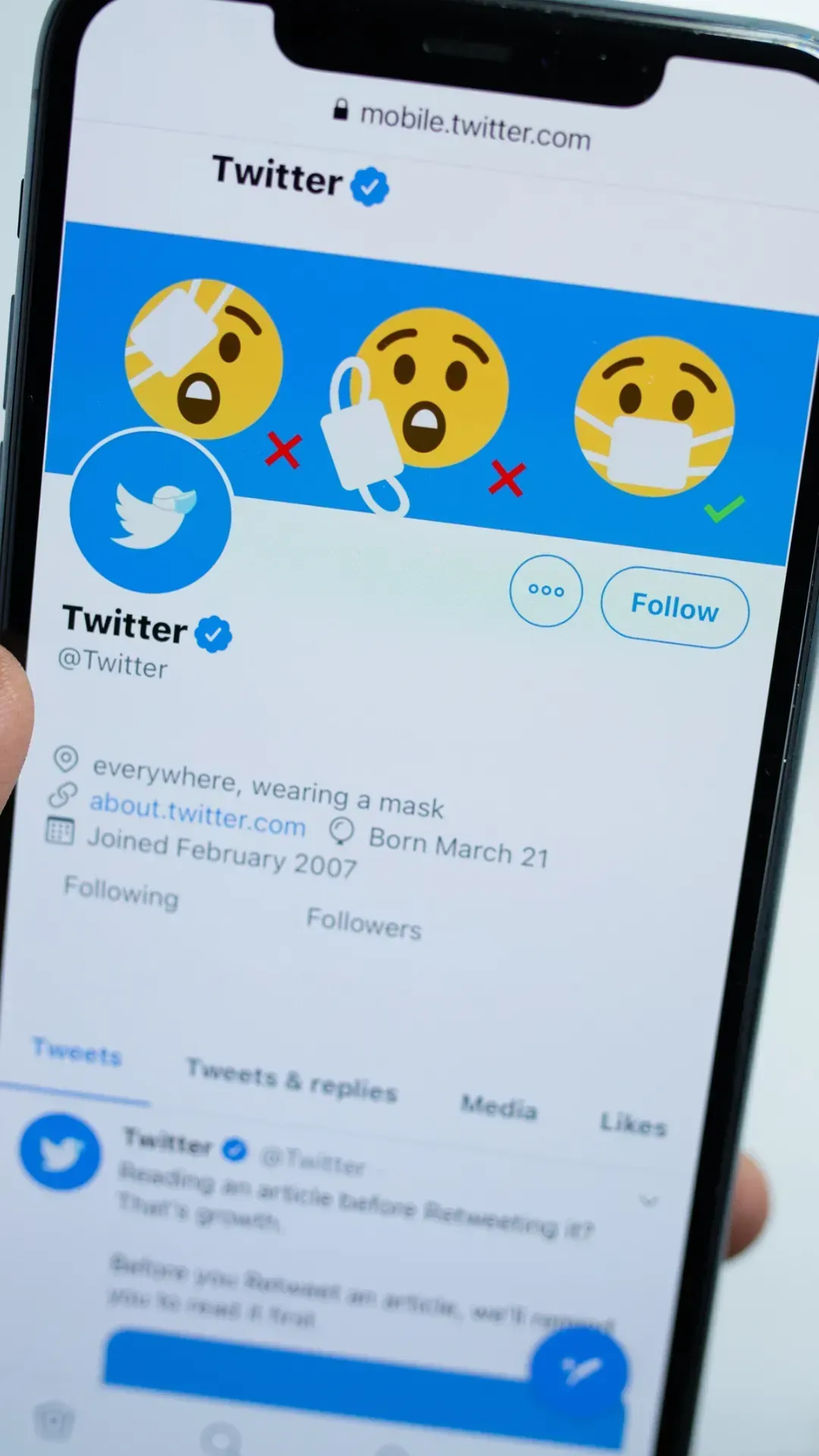 A person is holding a cell phone with the twitter app open