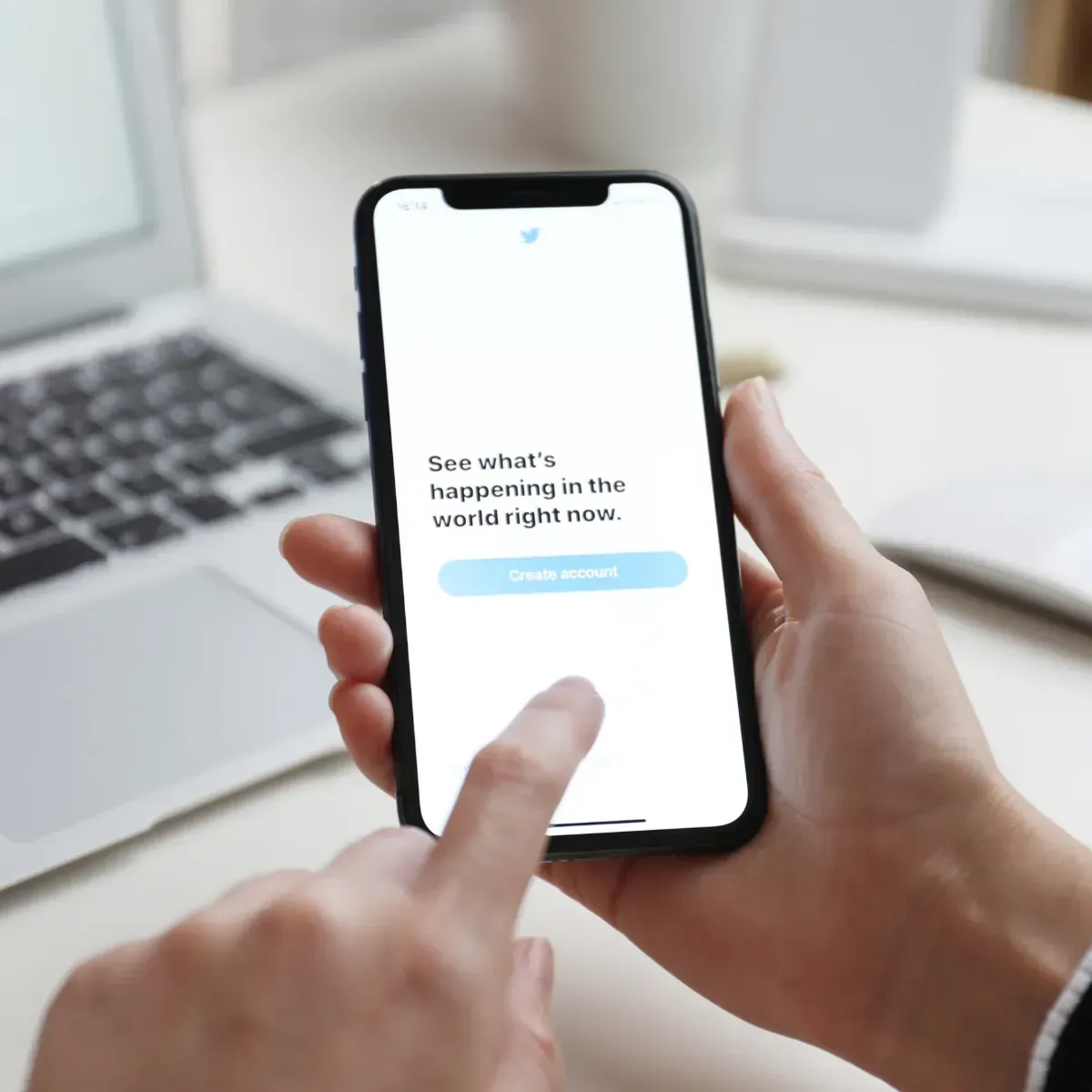 A person is holding a cell phone that says see what 's happening in the word right now