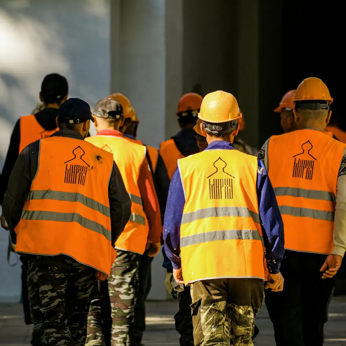 A group of construction workers wearing orange vests and hard hats