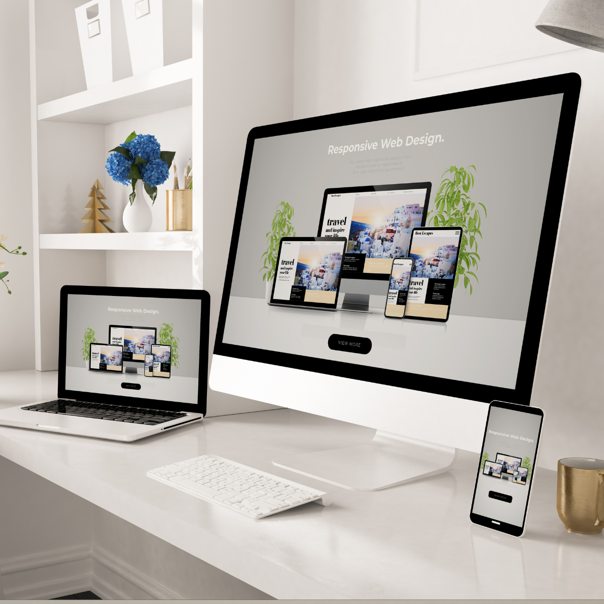 A computer , laptop , and cell phone are on a desk.