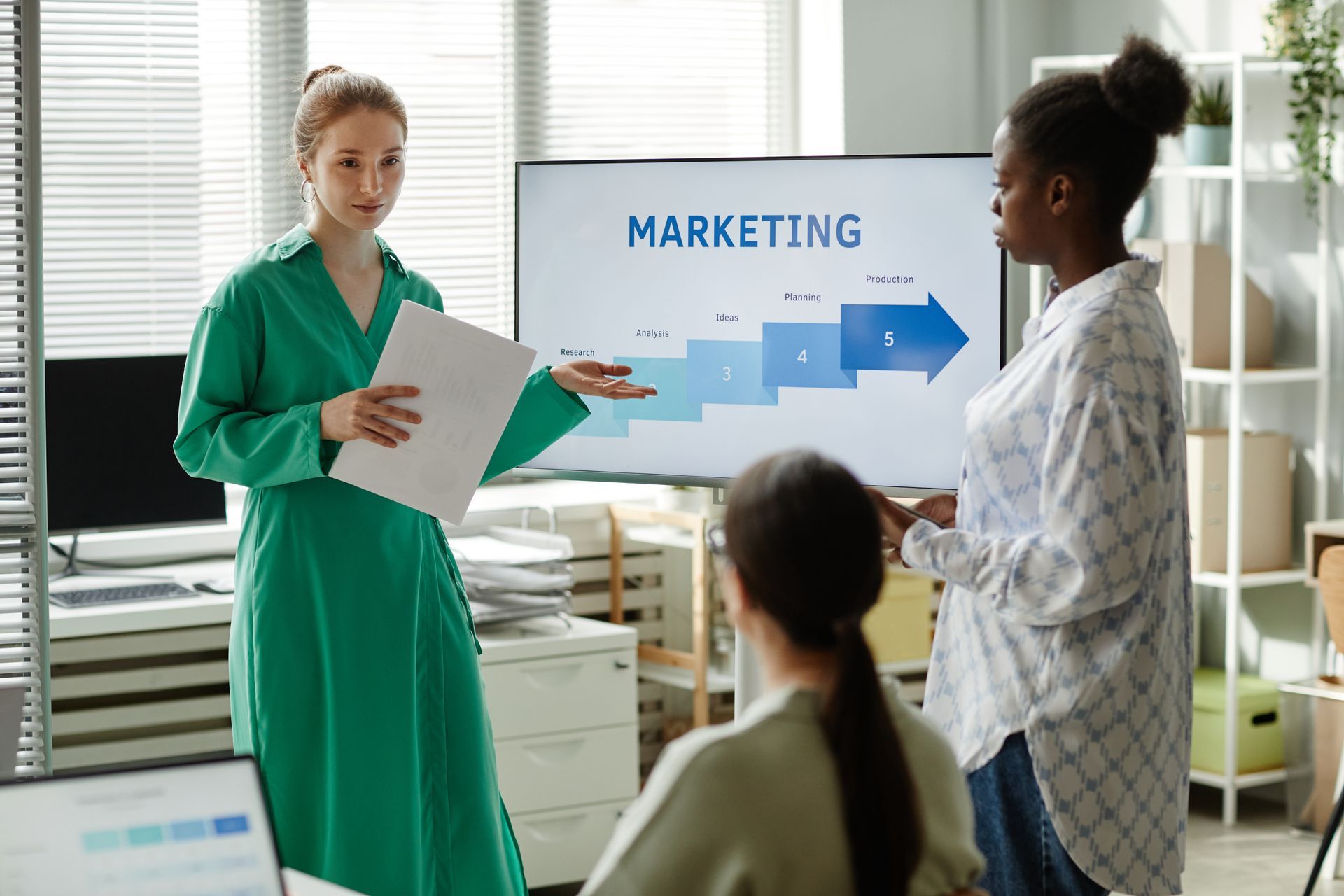 A woman is giving a presentation on marketing to a group of people.