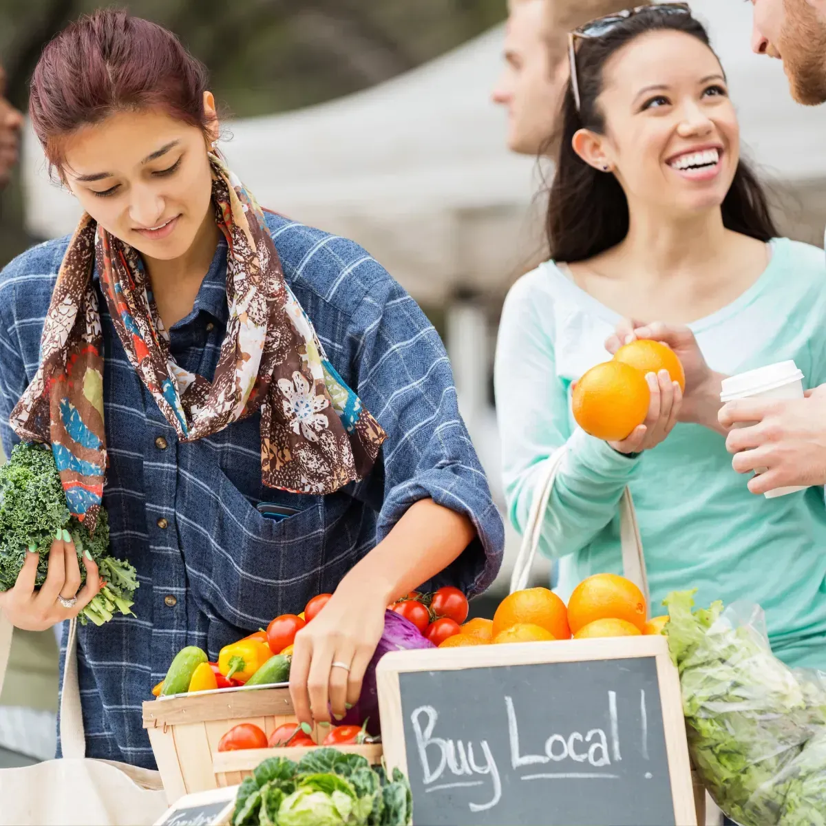 A group of people are standing around a sign that says buy local