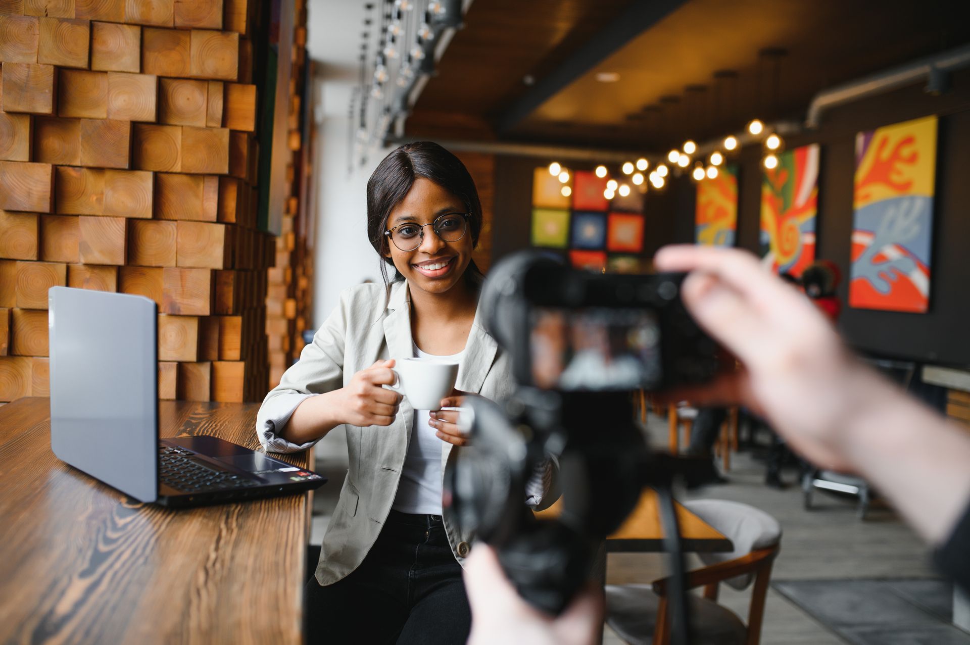 A man is taking a picture of a woman holding a cup of coffee.