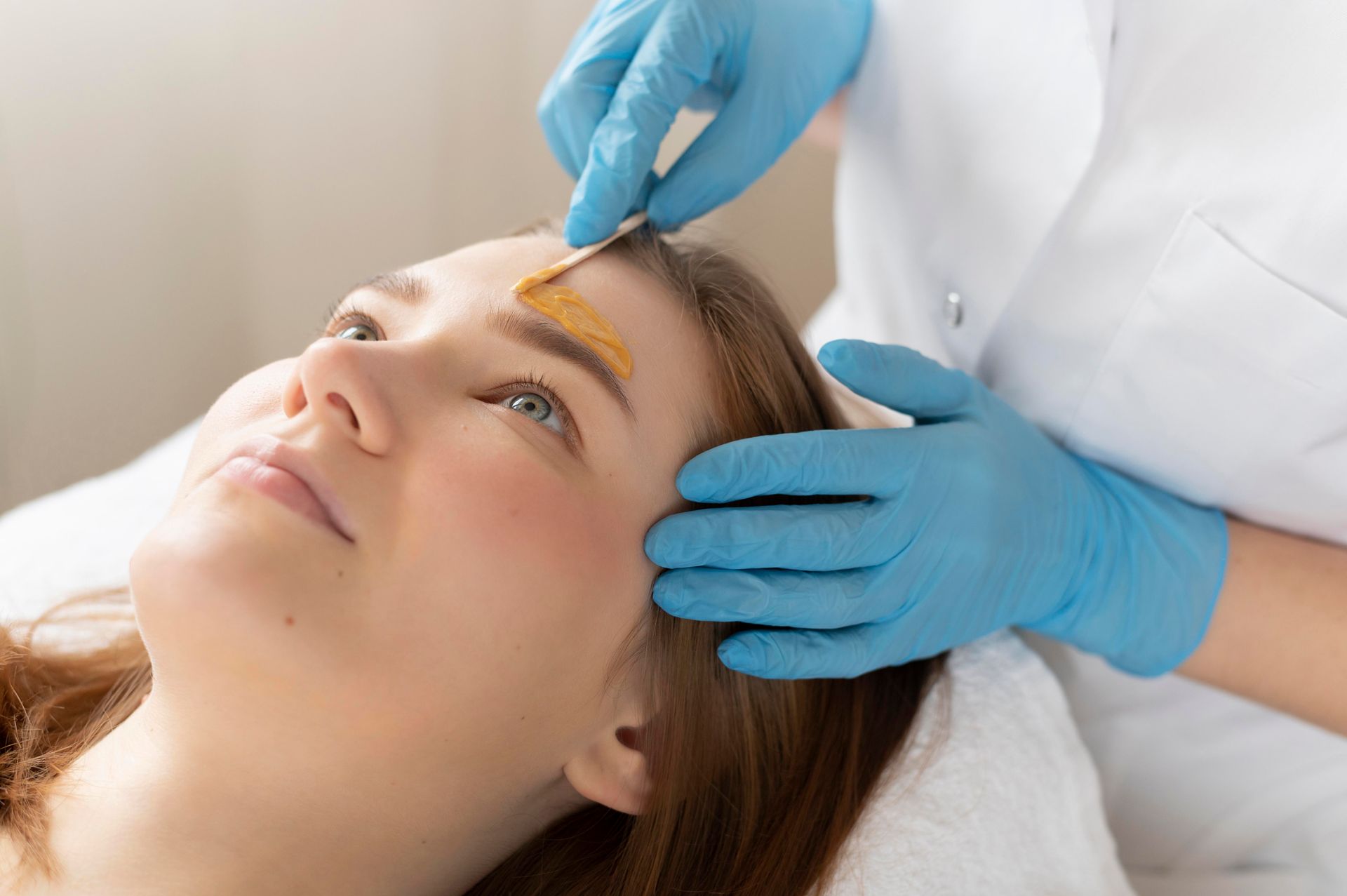 A woman is getting her eyebrows waxed in a beauty salon.