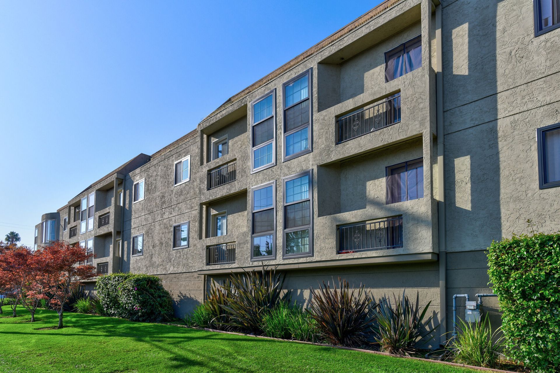 A large apartment building with a lush green lawn in front of it.