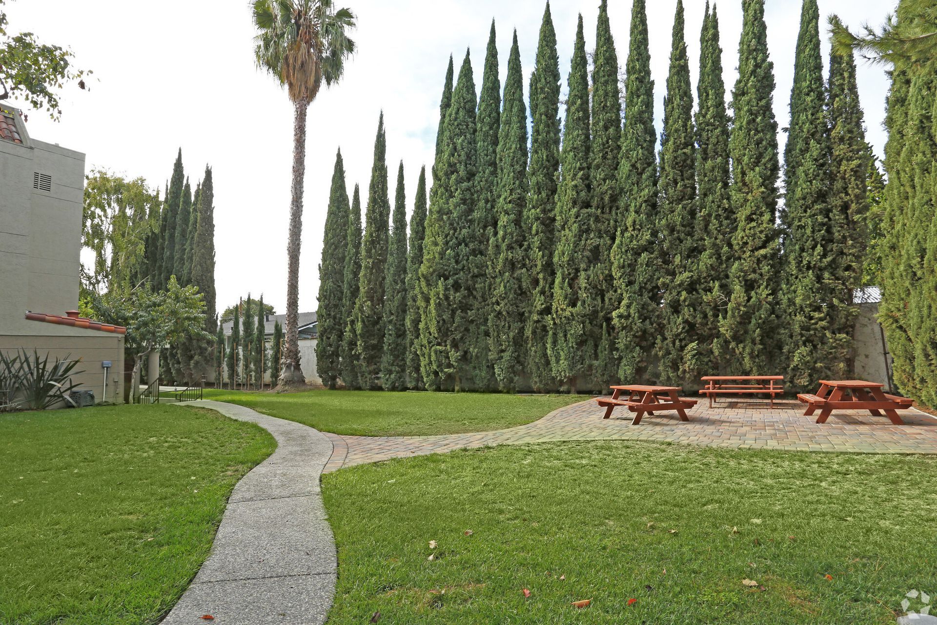 A path leading to a picnic area surrounded by trees and a building.