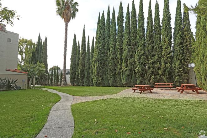 A path leading to a picnic area surrounded by trees and a building.