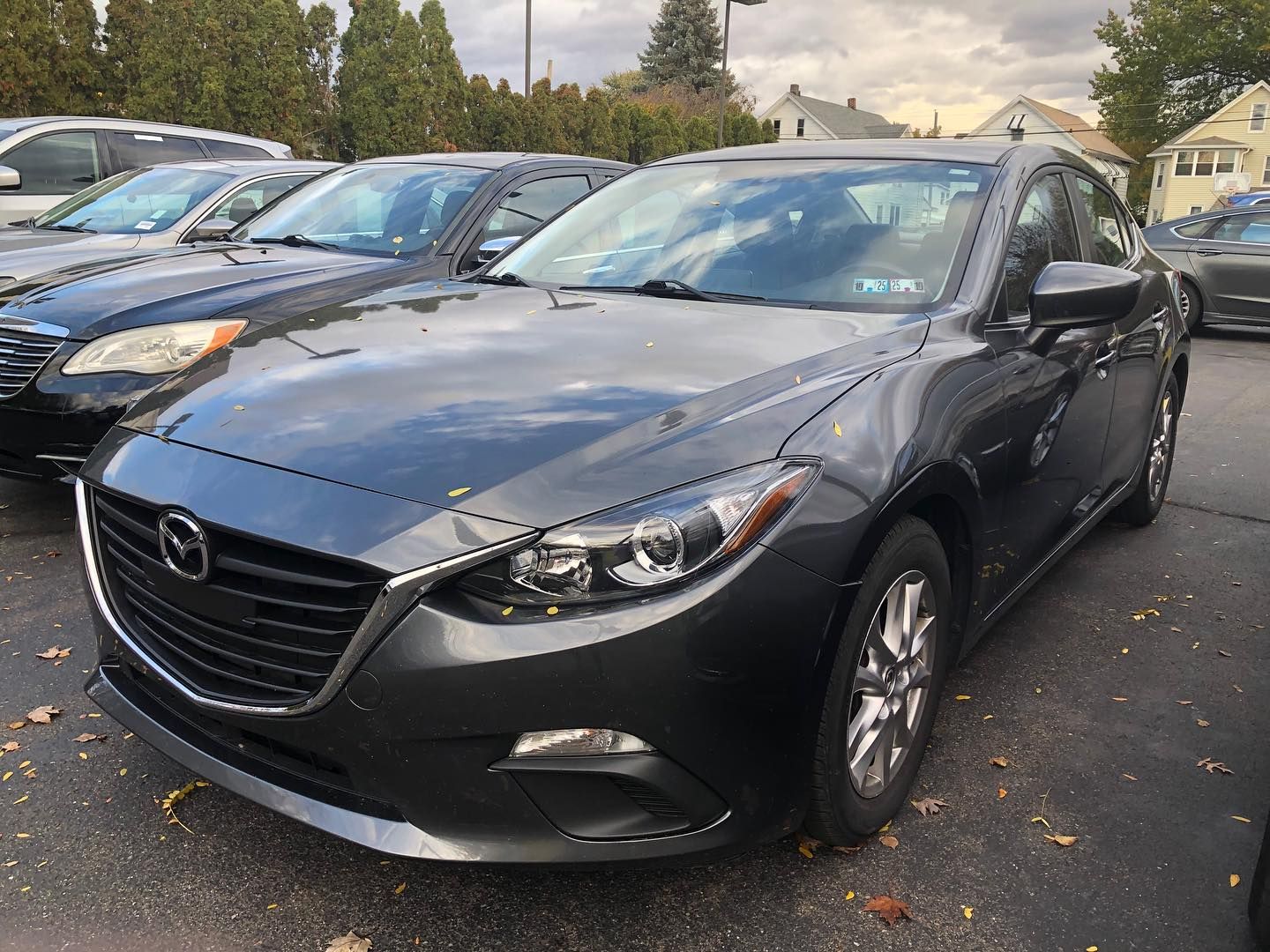 Gray Mazda 3 sedan parked outside on a cloudy day.