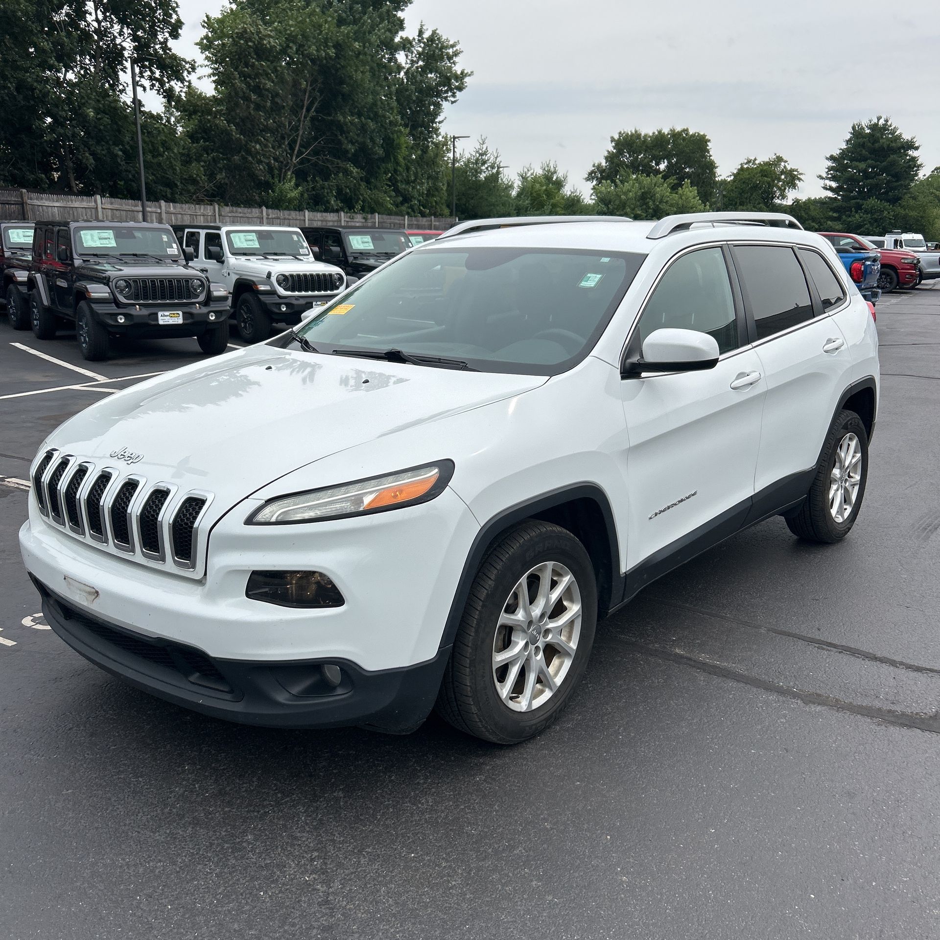 White Jeep SUV parked in a lot, front-left view on a wet pavement.