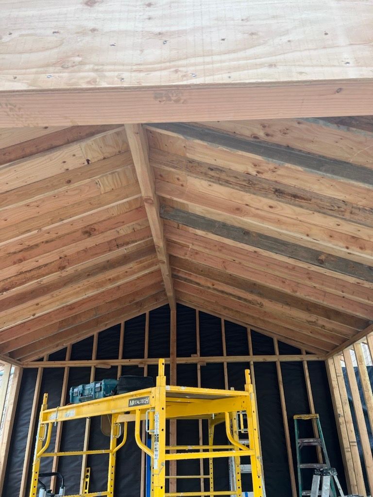 Wooden roof construction; framing, beams, and scaffolding visible.