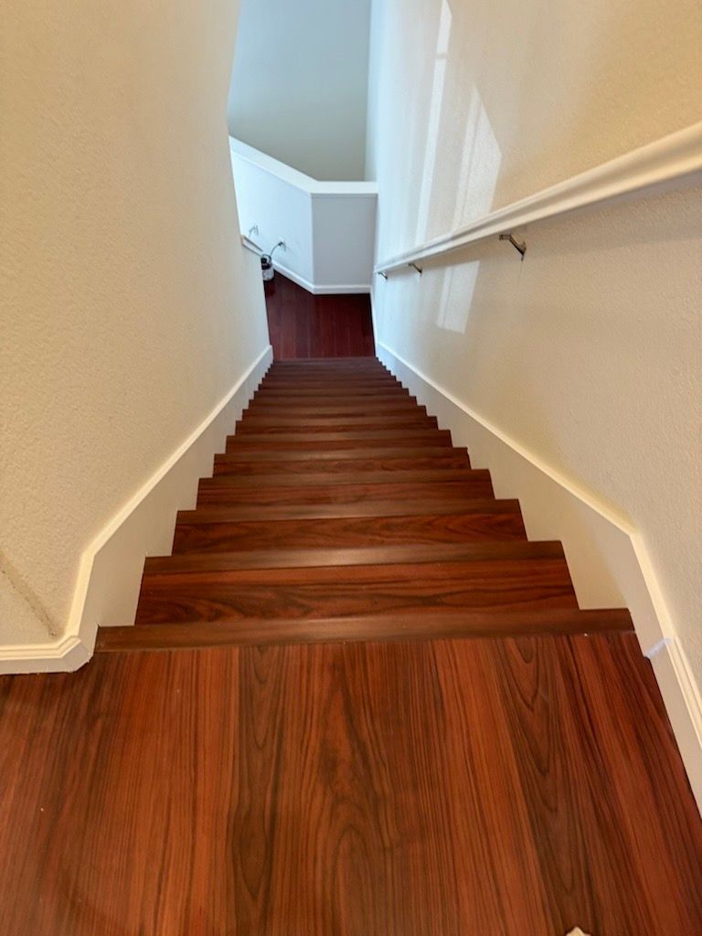 Wooden staircase with handrail, leading upward between white walls. Wooden staircase with handrail, leading upward between white walls.