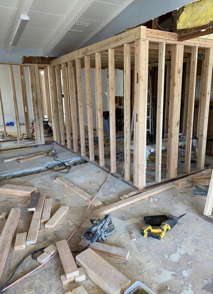 Interior of a building under construction, showing wooden wall framing on a concrete floor.