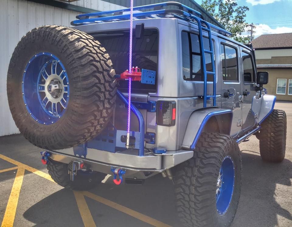 Silver off-road Jeep with oversized tires parked in a sunny parking lot