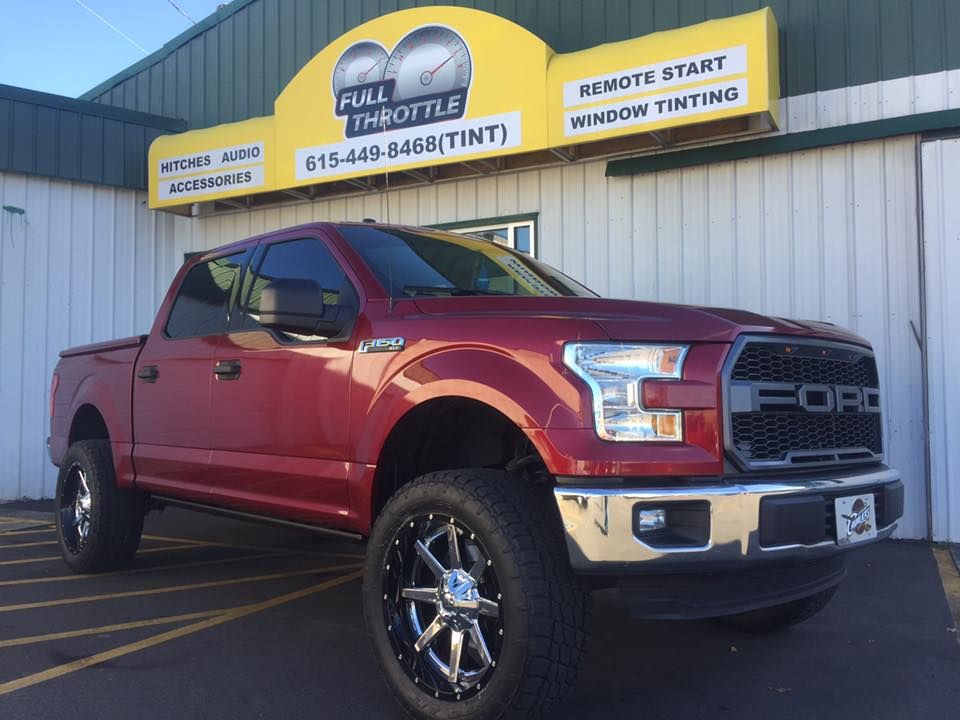 Red Ford F-150 pickup parked outside a window tinting shop.