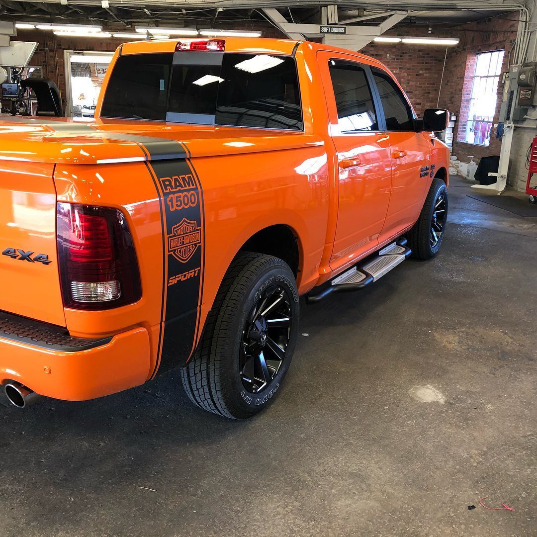 Bright orange pickup truck with black wheels parked inside a garage or workshop.