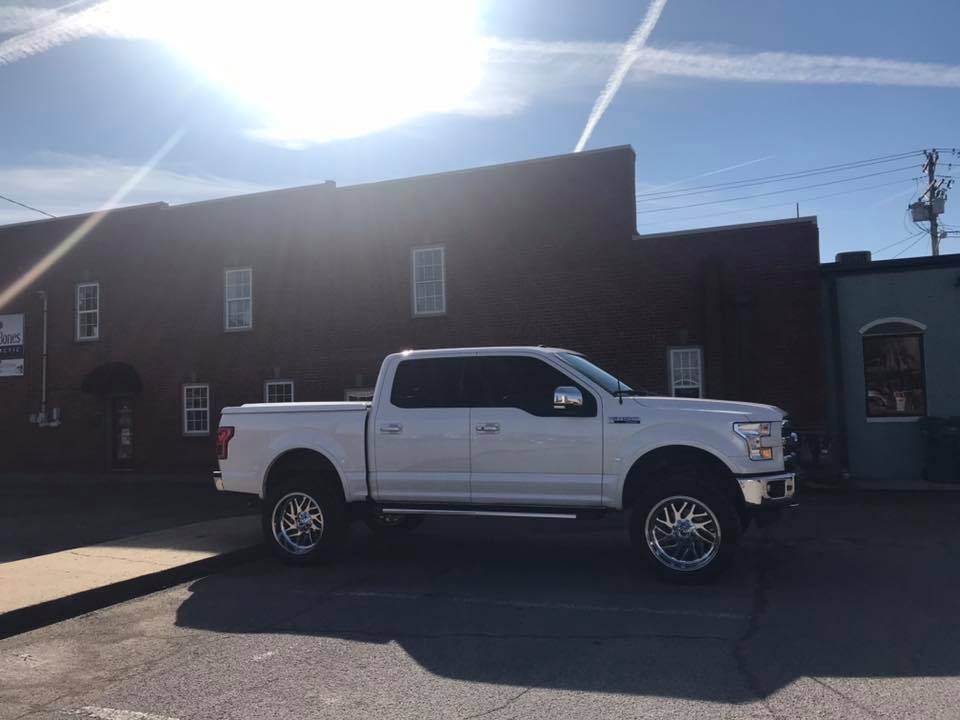 White pickup truck parked in front of a brick building on a sunny street