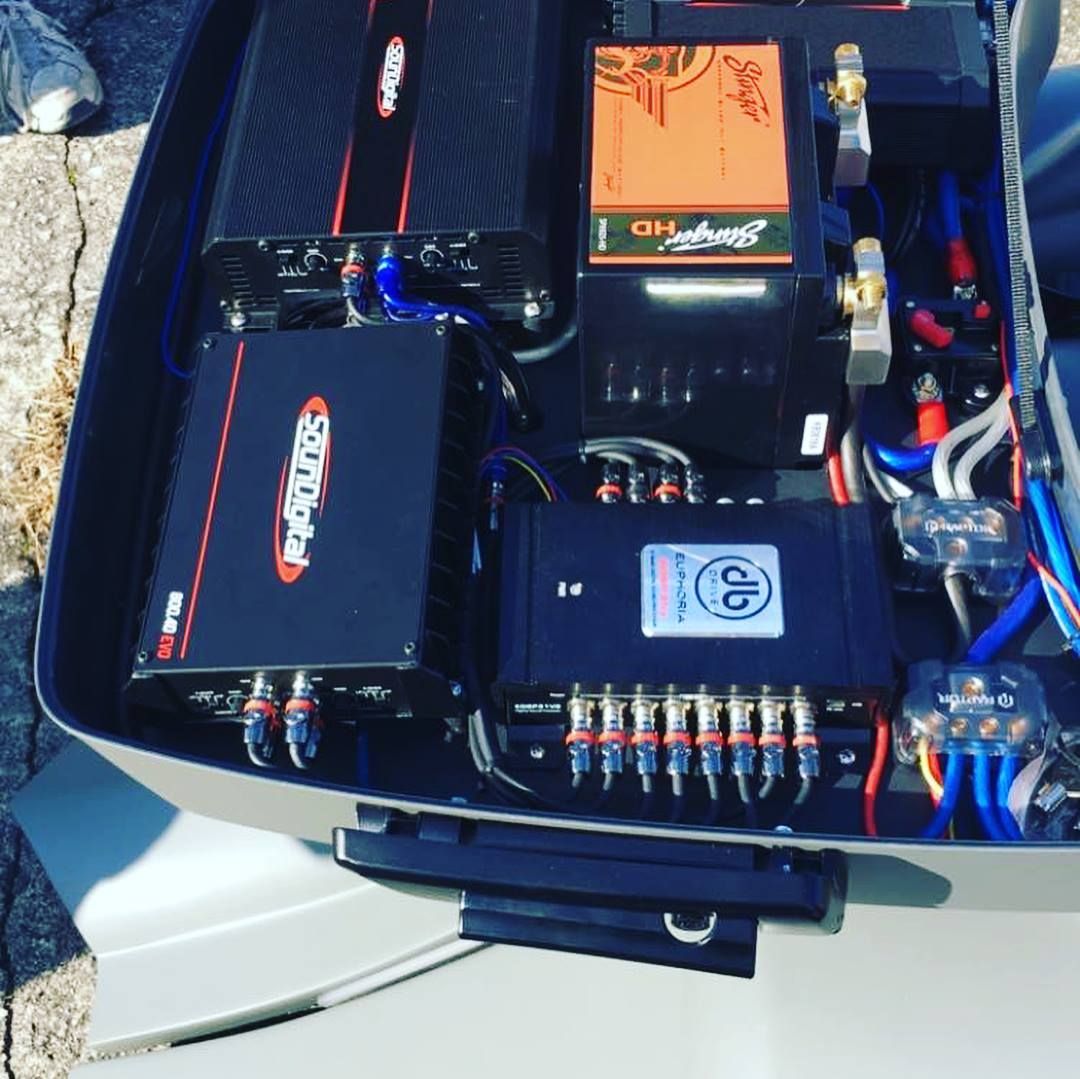 Open car trunk with audio system components, amplifiers, wiring, and fuse block installed.