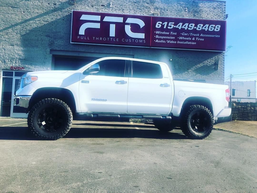 White pickup truck parked in front of a purple FTC sign on a sunny day
