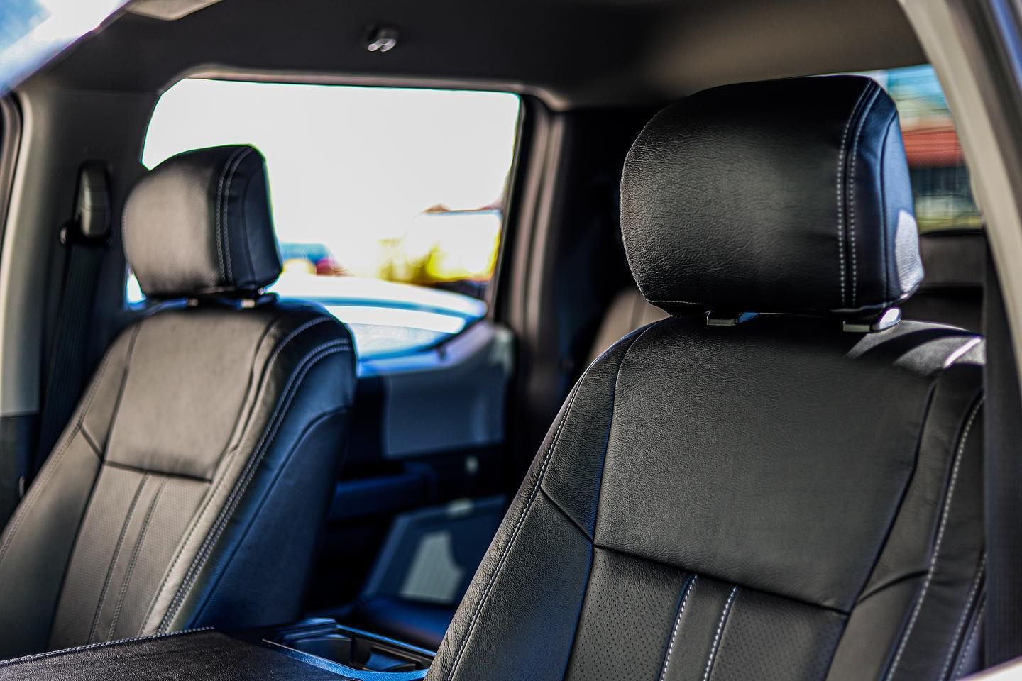 Car interior with two black leather front seats and a view through the windows