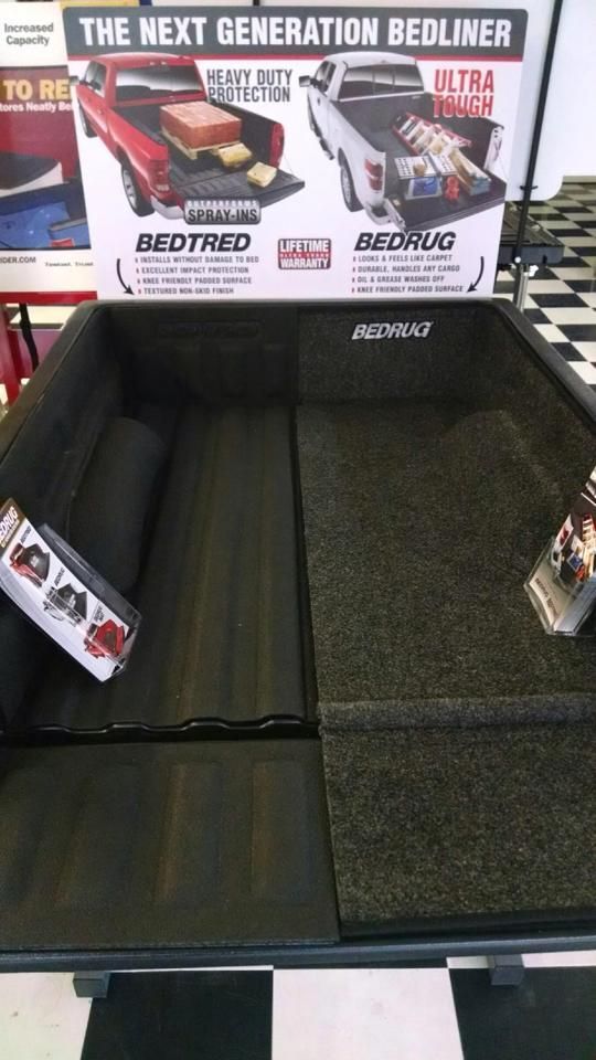Bed liner display booth showing black and green pickup truck bed liners with product signage above