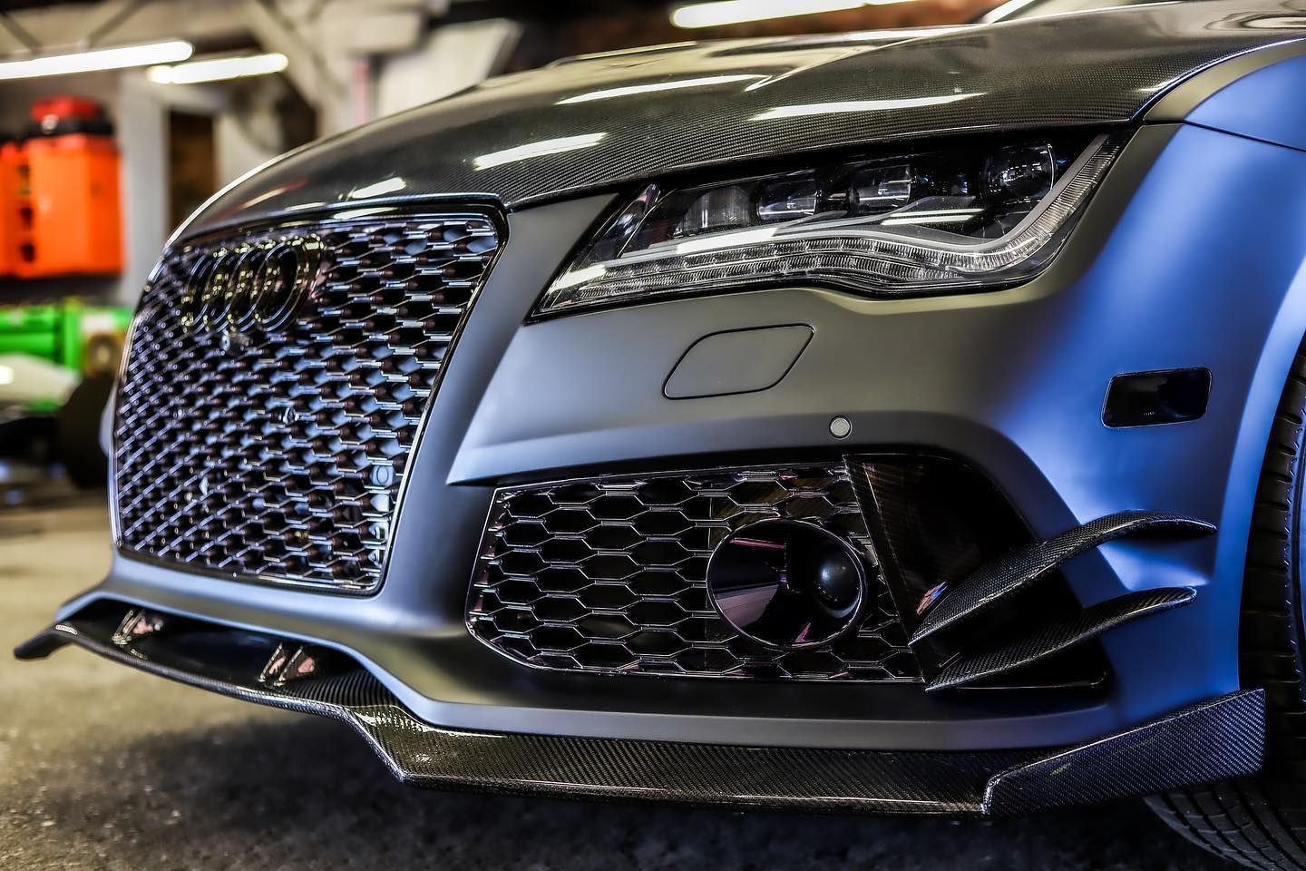 Close-up of a silver sports car front grille and headlight at a car show