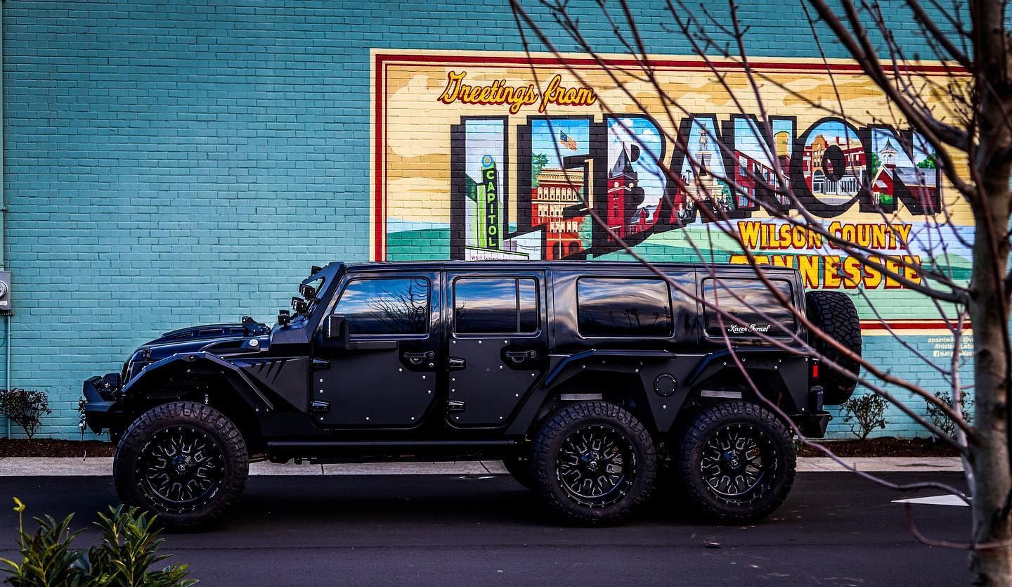 Black SUV parked along a blue wall with a colorful mural in the background