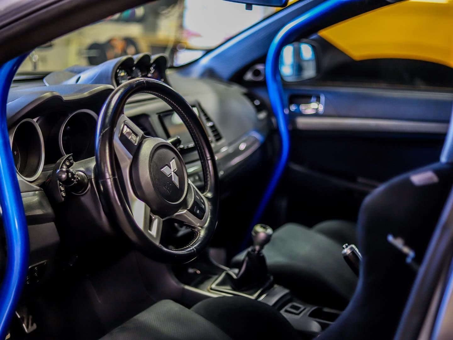Blue-lit sports car interior with racing-style steering wheel and black seats