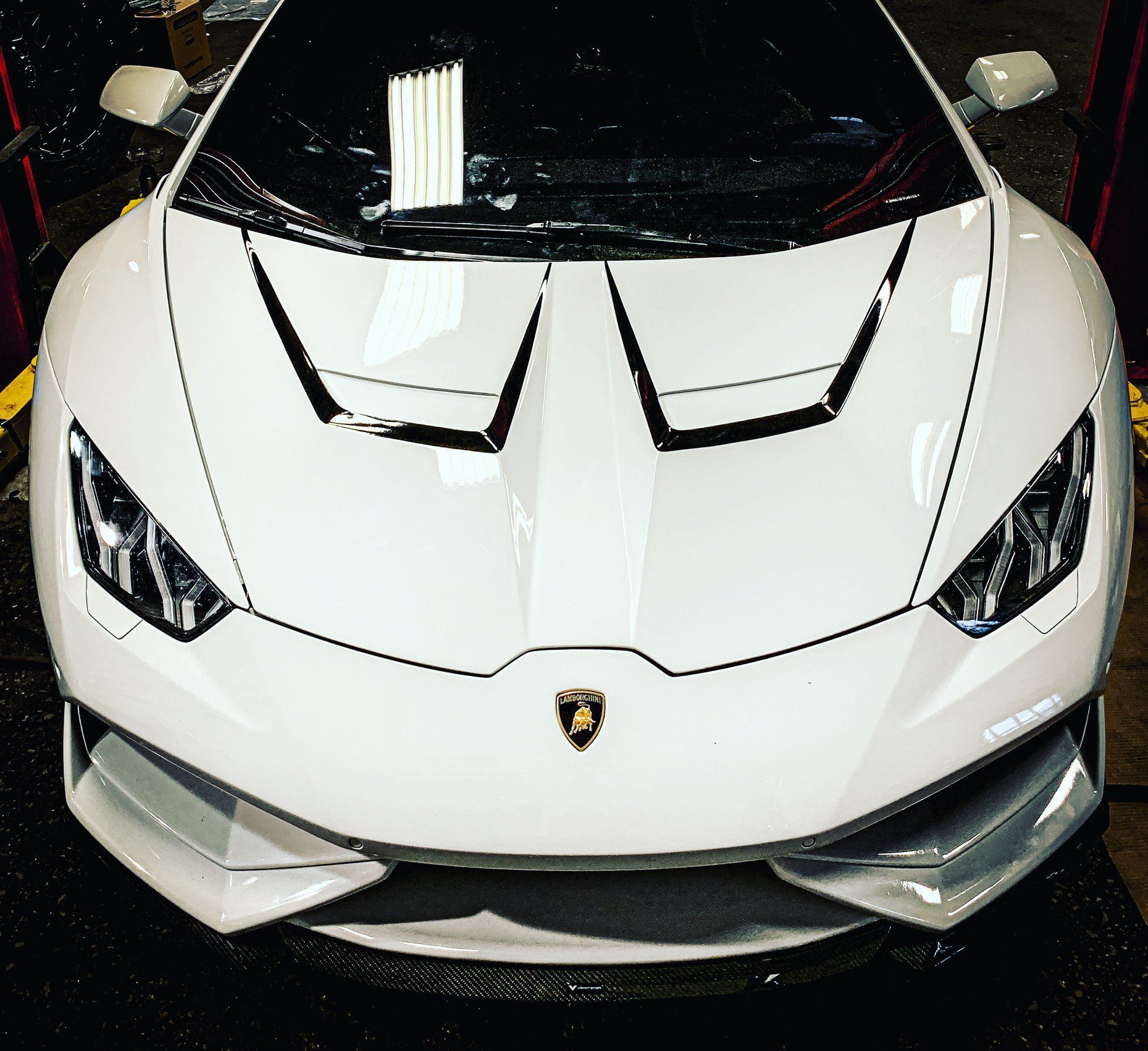 Front view of a white Lamborghini sports car with sharp headlights and a black windshield.